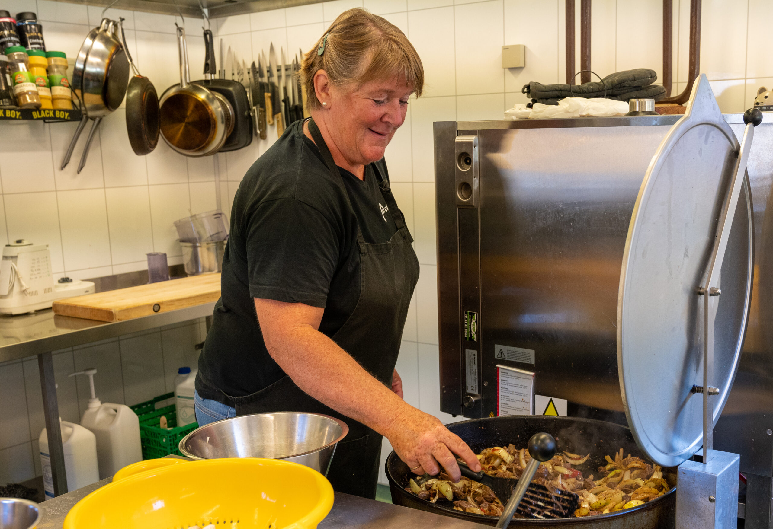 Turid står ved en stor kjele og steker mat