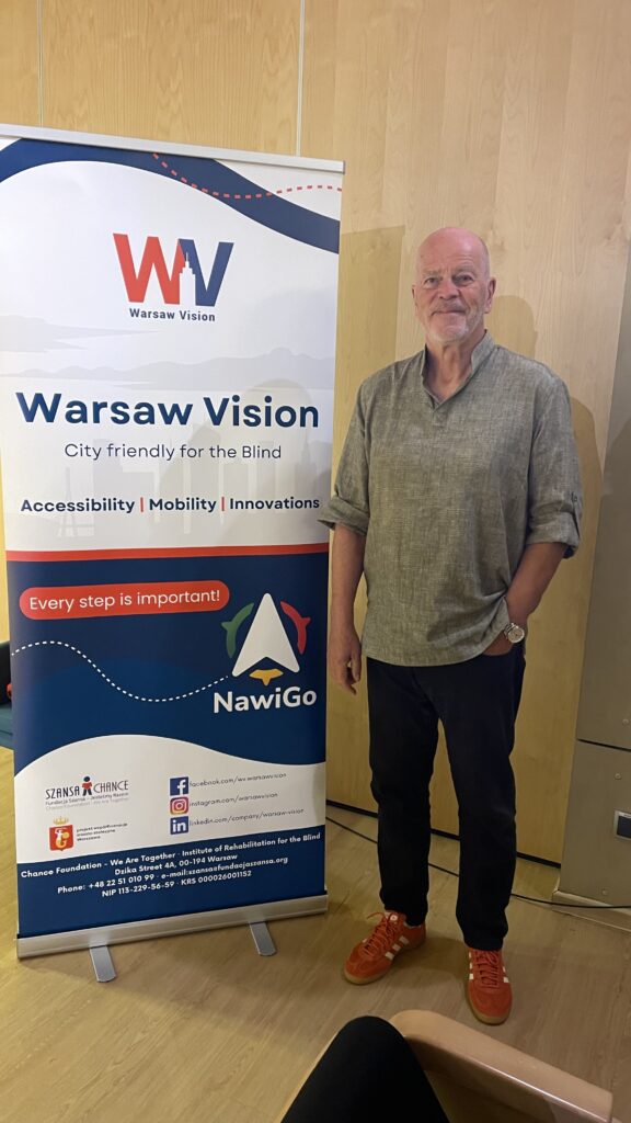 Rolf Lund står ved side nav en roll-uo med teksten Warsaw vision